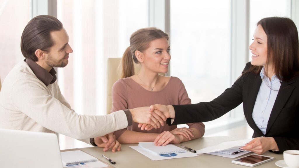 How to choose an SEO and GEO agency: three professionals shaking hands at a meeting table after closing a partnership