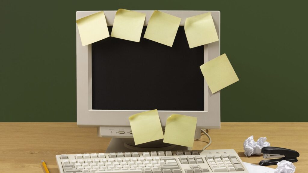 Remove outdated content from Google: old computer covered in sticky notes on an office desk